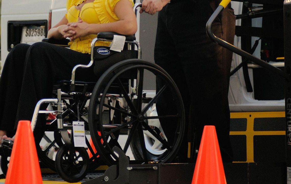 A transport service assisting a person in a wheelchair outdoors, focusing on accessibility.