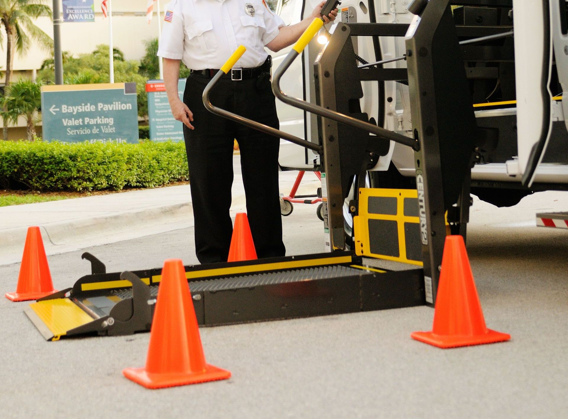 Safety officer demonstrating the use of a wheelchair lift in a van at a facility.